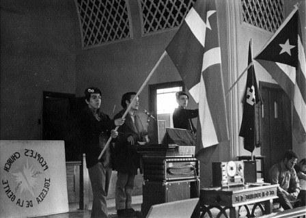 Young men holding speaking and holding flags at the Iglesia de la Gente People's Church